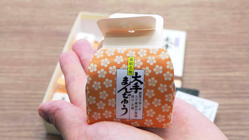手のひらにのせられた大手饅頭伊部屋の商品「大手まんぢゅう」のパッケージ