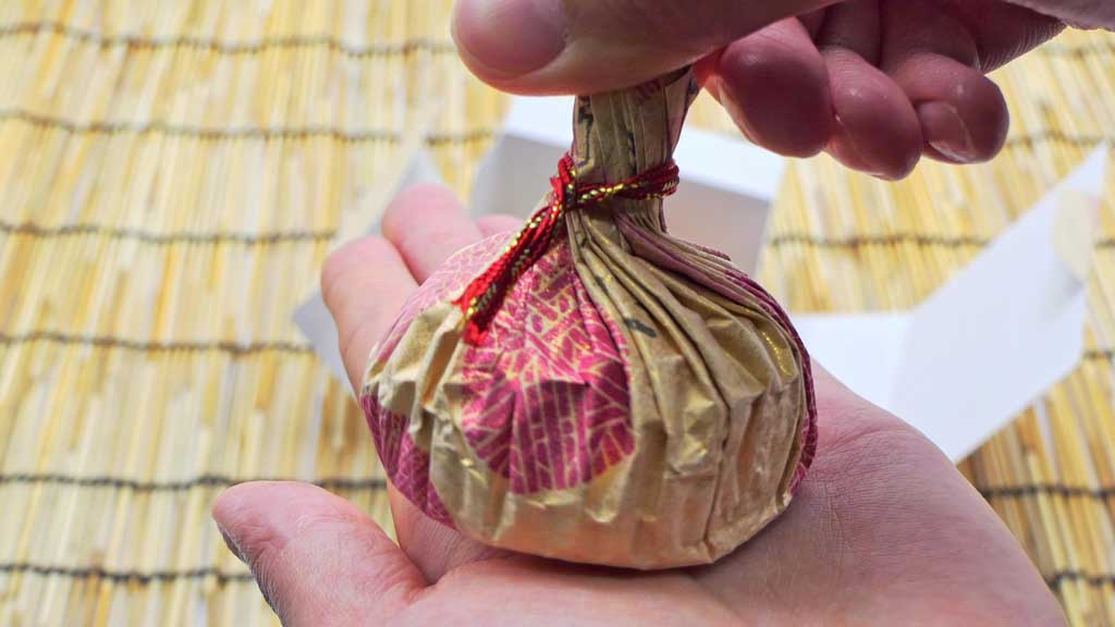 手のひらに乗せられた菓子処ひらいの商品「良寛てまり」のパッケージ