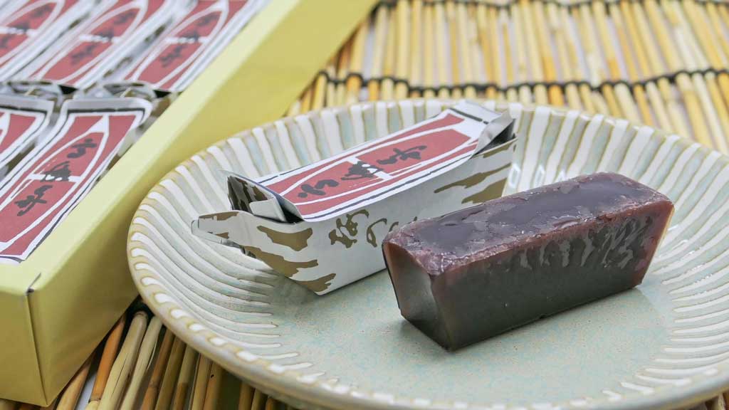 お皿に乗せられた古見屋羊羹の商品「高瀬舟羊羹」とそのパッケージ